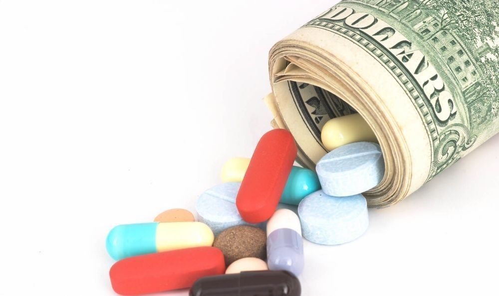 Closeup Money rolled up with pills falling out, high cost, expensive healthcare