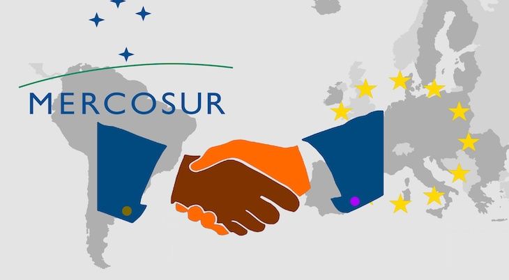 Trade agreement between Mercosur and the EU - On the maps of South America and Europe are the respective symbols. In front of it the illustration of a handshake as a symbol for a contract.