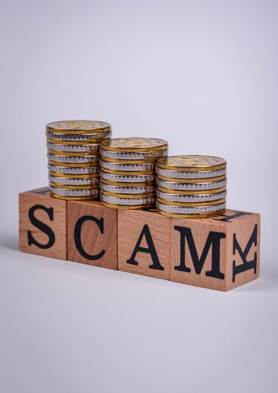 The inscription Scam made of wooden cubes on a plain background